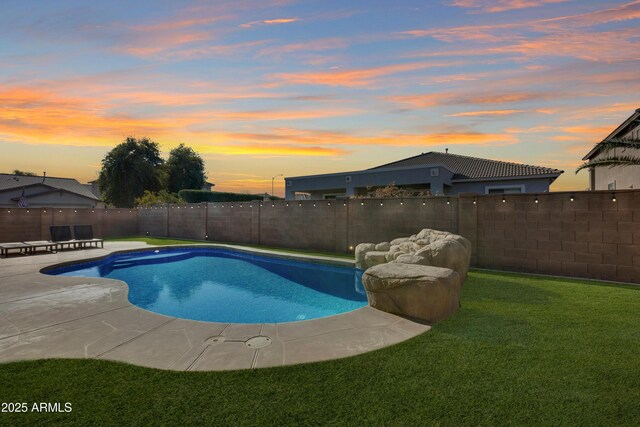 pool at dusk featuring a lawn and a patio