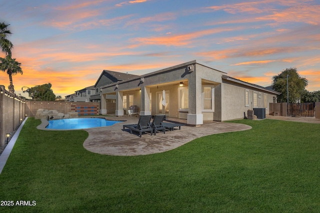 back house at dusk featuring a lawn, cooling unit, a patio, and a fenced in pool