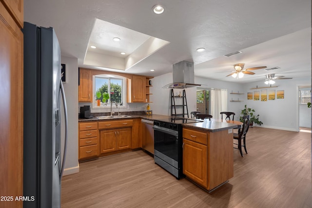 kitchen featuring stainless steel appliances, island range hood, a peninsula, dark countertops, and light wood-style floors
