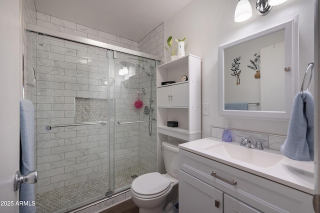 bathroom with toilet, a shower stall, and vanity