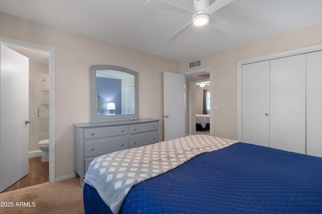 bedroom featuring a closet, light carpet, ensuite bath, a ceiling fan, and baseboards