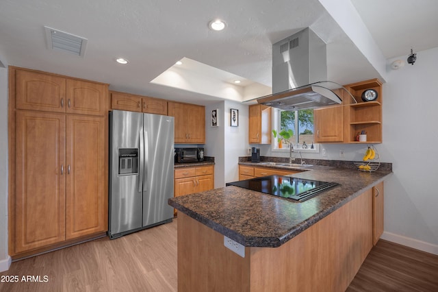 kitchen featuring black appliances, island range hood, a peninsula, light wood-style flooring, and a sink