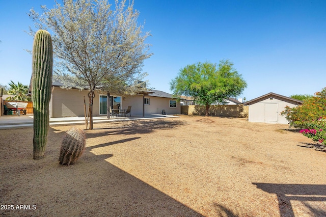 view of yard with a storage shed, a patio, an outbuilding, and fence