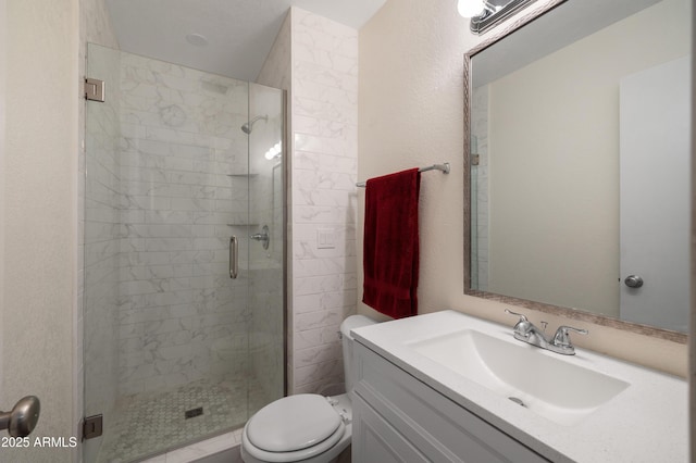 bathroom featuring toilet, a stall shower, and vanity