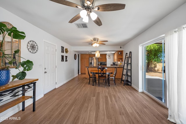 dining room with light wood-style flooring, ceiling fan, and baseboards