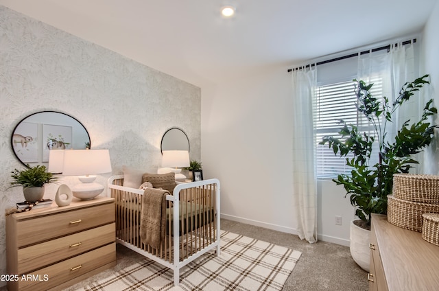 bedroom with a crib, baseboards, and light carpet