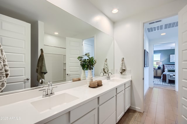 full bath featuring double vanity, recessed lighting, baseboards, and a sink