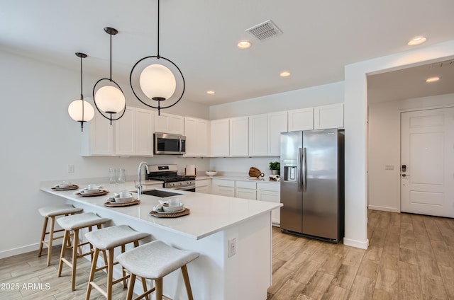 kitchen with visible vents, a sink, appliances with stainless steel finishes, a peninsula, and light countertops