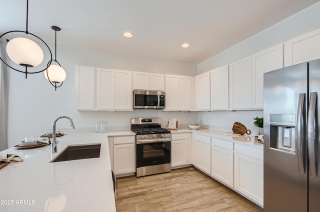 kitchen featuring a sink, stainless steel appliances, light countertops, white cabinets, and light wood-type flooring