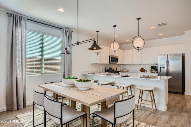 kitchen featuring visible vents, a peninsula, light wood-style flooring, white cabinets, and appliances with stainless steel finishes