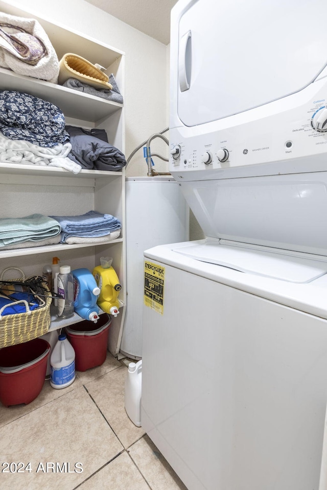 laundry area featuring light tile patterned floors and stacked washer and clothes dryer