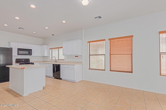 kitchen featuring white cabinets, light tile patterned floors, black appliances, a center island, and sink