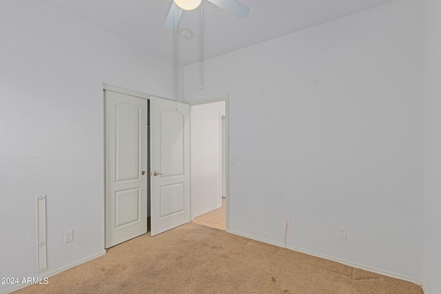 unfurnished bedroom with light carpet, a closet, and ceiling fan