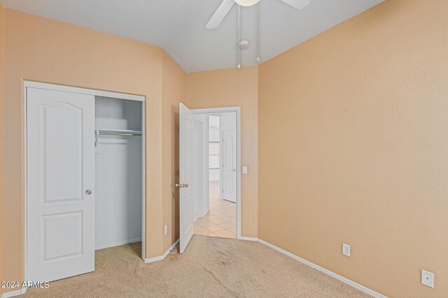 unfurnished bedroom featuring ceiling fan, light colored carpet, and a closet