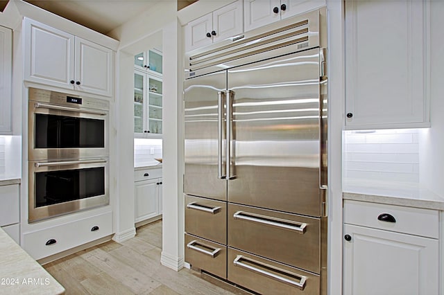 kitchen featuring backsplash, white cabinetry, and stainless steel appliances