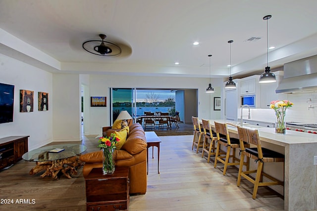 living room with light hardwood / wood-style floors, ceiling fan, and sink