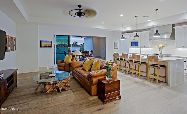 living room featuring light hardwood / wood-style floors, ceiling fan, and sink