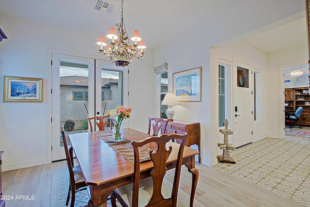 dining room with light hardwood / wood-style flooring and a notable chandelier