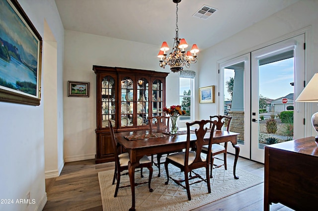 dining area featuring a chandelier, french doors, and hardwood / wood-style flooring