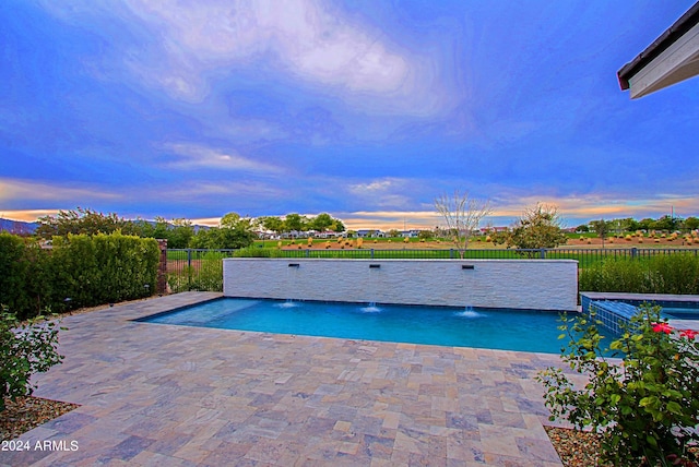 pool at dusk featuring a patio