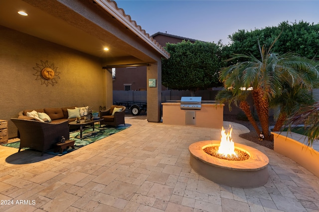 patio terrace at dusk with grilling area and an outdoor living space with a fire pit