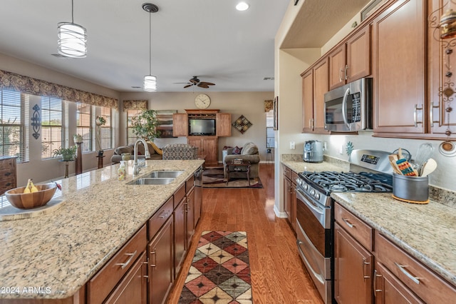 kitchen with sink, wood-type flooring, decorative light fixtures, a center island with sink, and stainless steel appliances