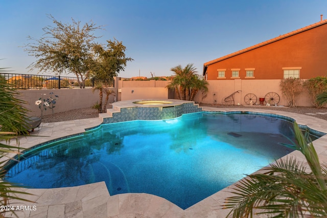 pool at dusk with an in ground hot tub