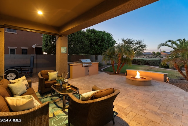 patio terrace at dusk featuring area for grilling and an outdoor living space with a fire pit