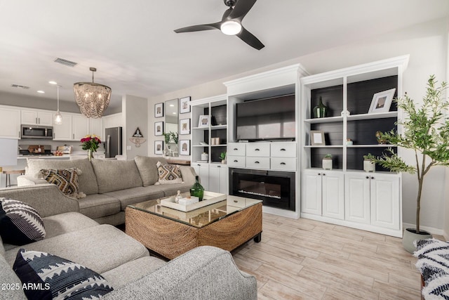 living area featuring recessed lighting, visible vents, light wood finished floors, and ceiling fan with notable chandelier