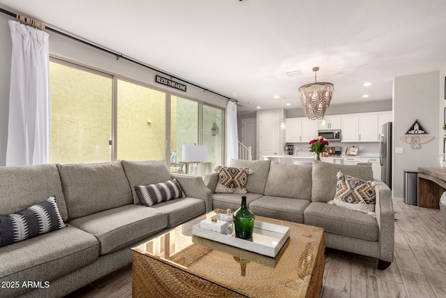 living room with a chandelier, recessed lighting, and light wood-style floors