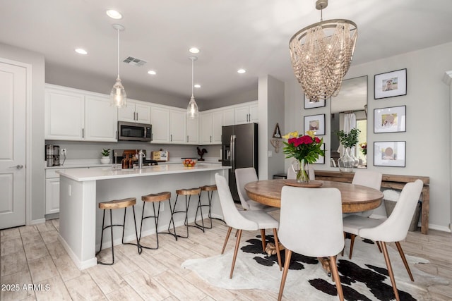 dining area with visible vents, a notable chandelier, recessed lighting, light wood-style floors, and baseboards