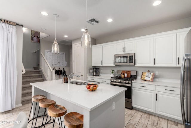 kitchen with white cabinetry, wood finish floors, visible vents, and stainless steel appliances