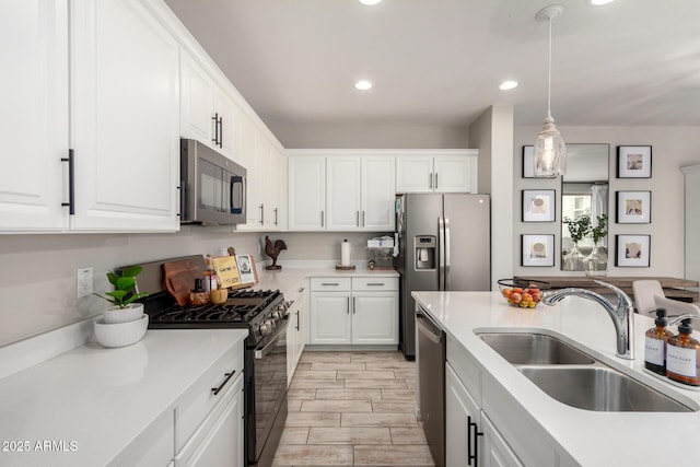 kitchen featuring pendant lighting, light countertops, appliances with stainless steel finishes, white cabinets, and a sink