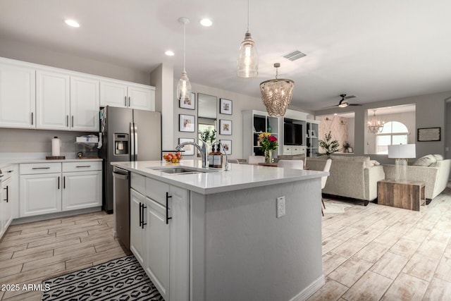 kitchen featuring a sink, open floor plan, white cabinets, light countertops, and wood tiled floor