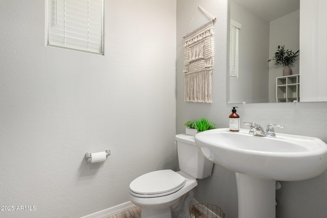 half bath with a sink, baseboards, and toilet