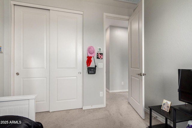 bedroom with light colored carpet, baseboards, and a closet