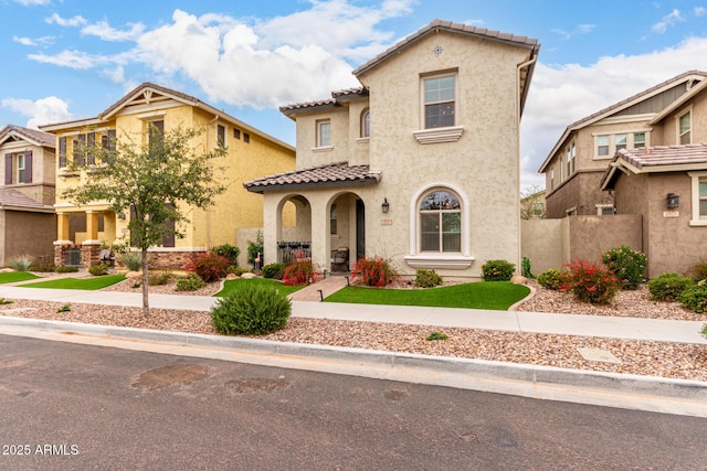 mediterranean / spanish home with a tile roof, fence, and stucco siding