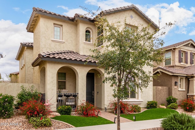 mediterranean / spanish-style house with stucco siding, covered porch, and a tile roof