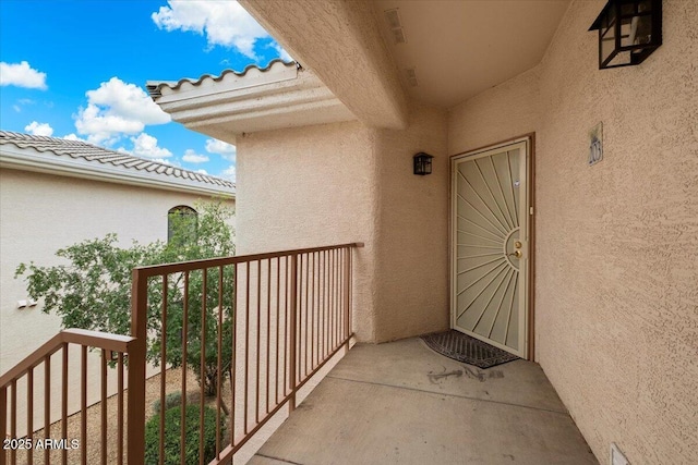 doorway to property featuring a tiled roof, a balcony, and stucco siding