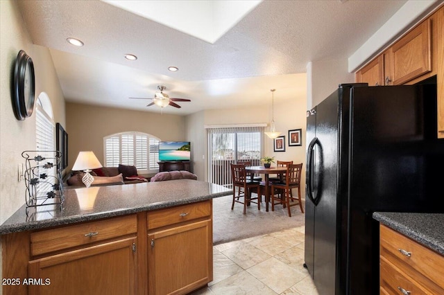 kitchen featuring open floor plan, brown cabinets, freestanding refrigerator, a peninsula, and hanging light fixtures