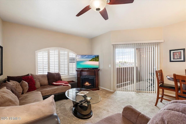 carpeted living room with a ceiling fan, plenty of natural light, a lit fireplace, and baseboards