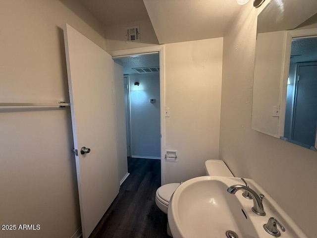 bathroom featuring visible vents, a sink, toilet, and wood finished floors