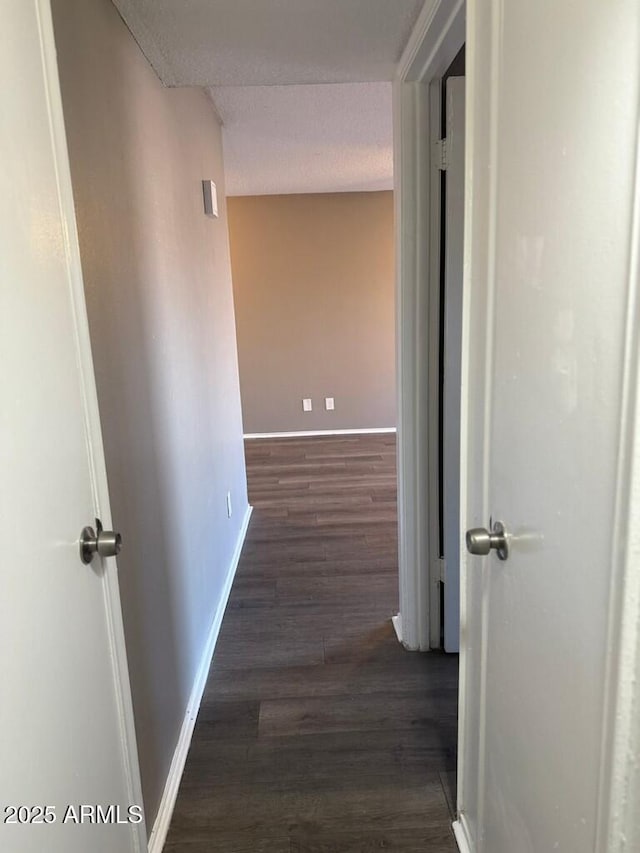 hall with dark wood-type flooring and baseboards