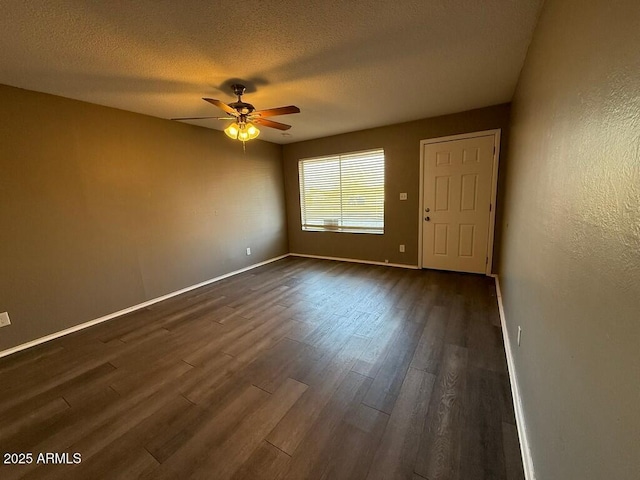 empty room featuring dark wood-style floors, baseboards, and a textured ceiling