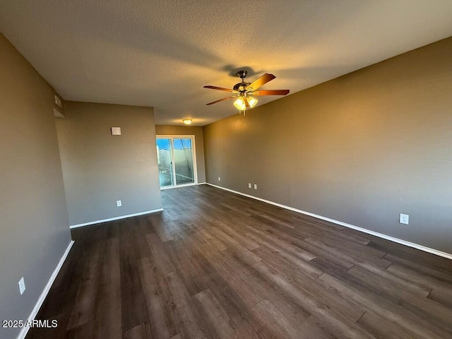 spare room with ceiling fan, a textured ceiling, baseboards, and dark wood-type flooring