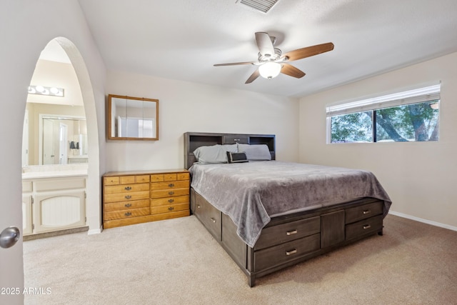 bedroom with baseboards, ensuite bathroom, ceiling fan, visible vents, and light carpet
