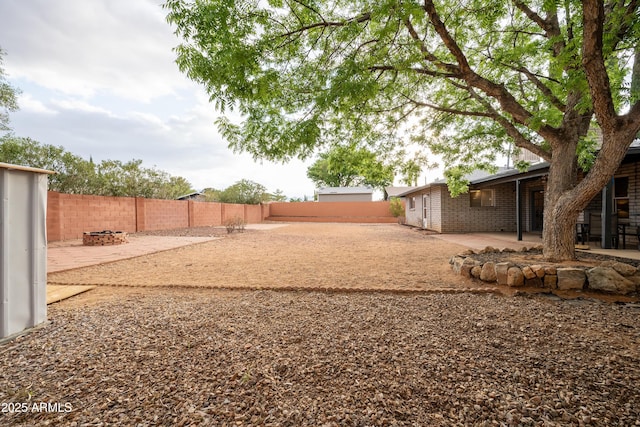 view of yard with a fenced backyard, a patio, and a fire pit