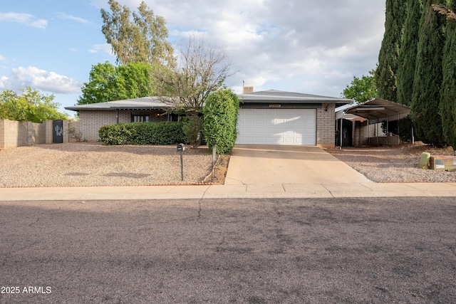 ranch-style home featuring an attached garage, concrete driveway, brick siding, and fence