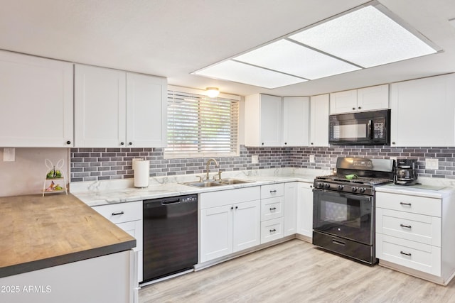 kitchen featuring a sink, tasteful backsplash, black appliances, and white cabinets