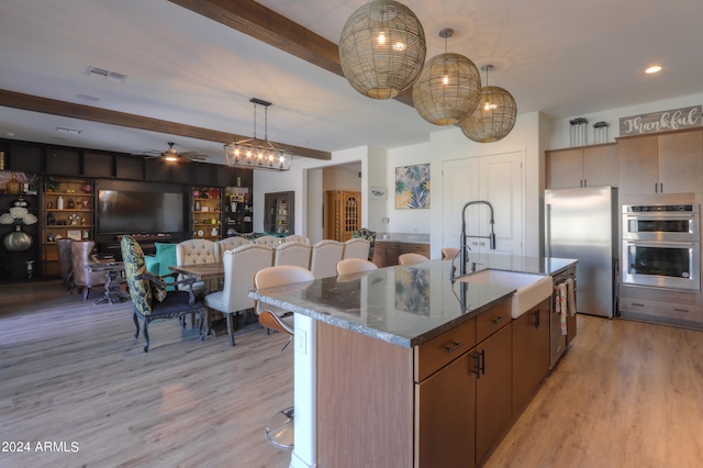 kitchen with appliances with stainless steel finishes, sink, a center island with sink, and light hardwood / wood-style floors